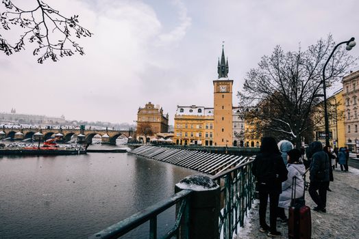 Snowy scene capturing Charles Bridge and historic Prague architecture in winter.