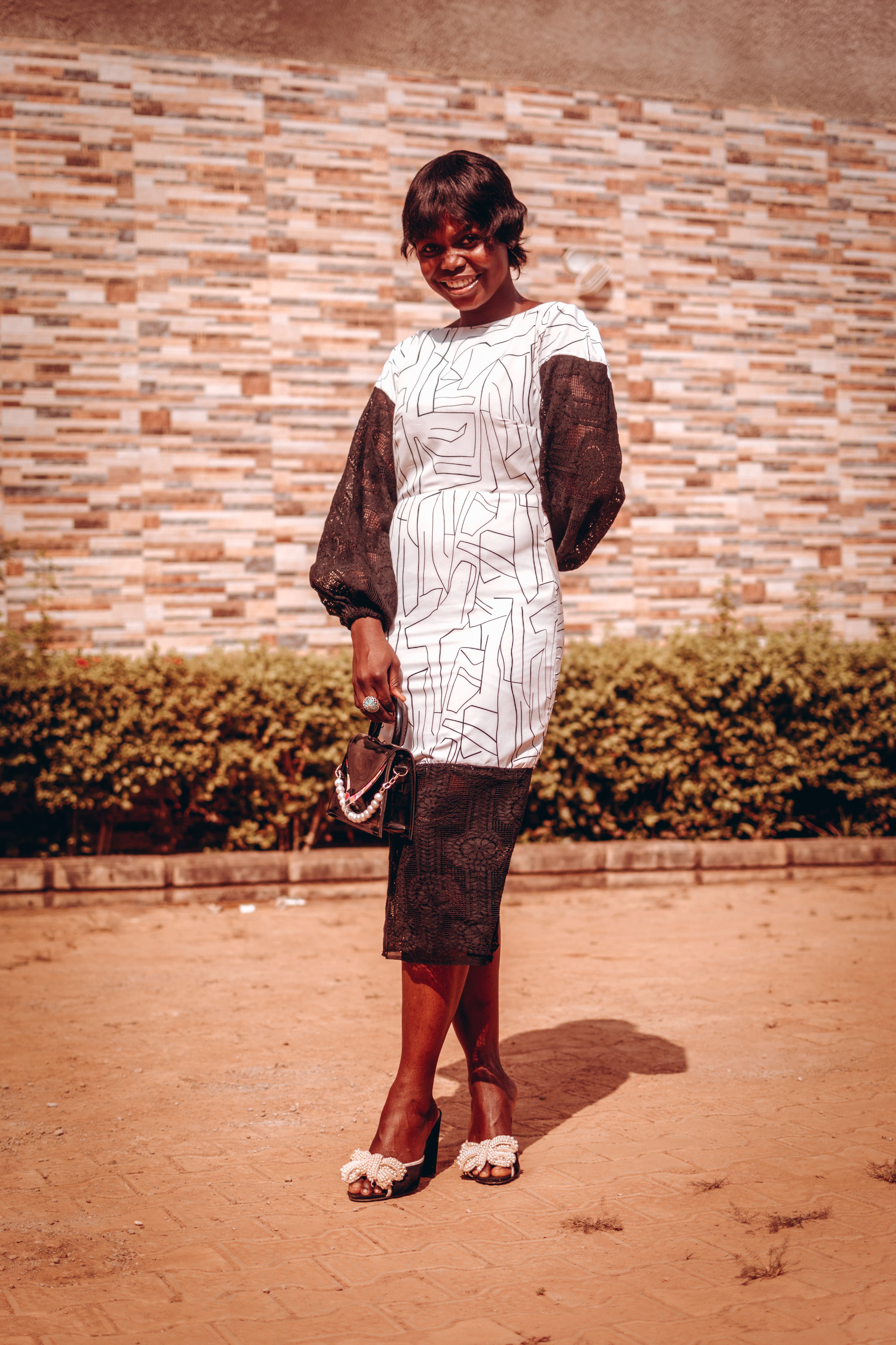 Portrait of a smiling woman in a fashionable dress, posing confidently outdoors in Keffi, Nigeria.
