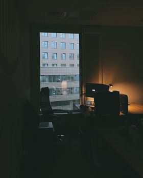 A dimly lit modern office interior with a window view of a building.
