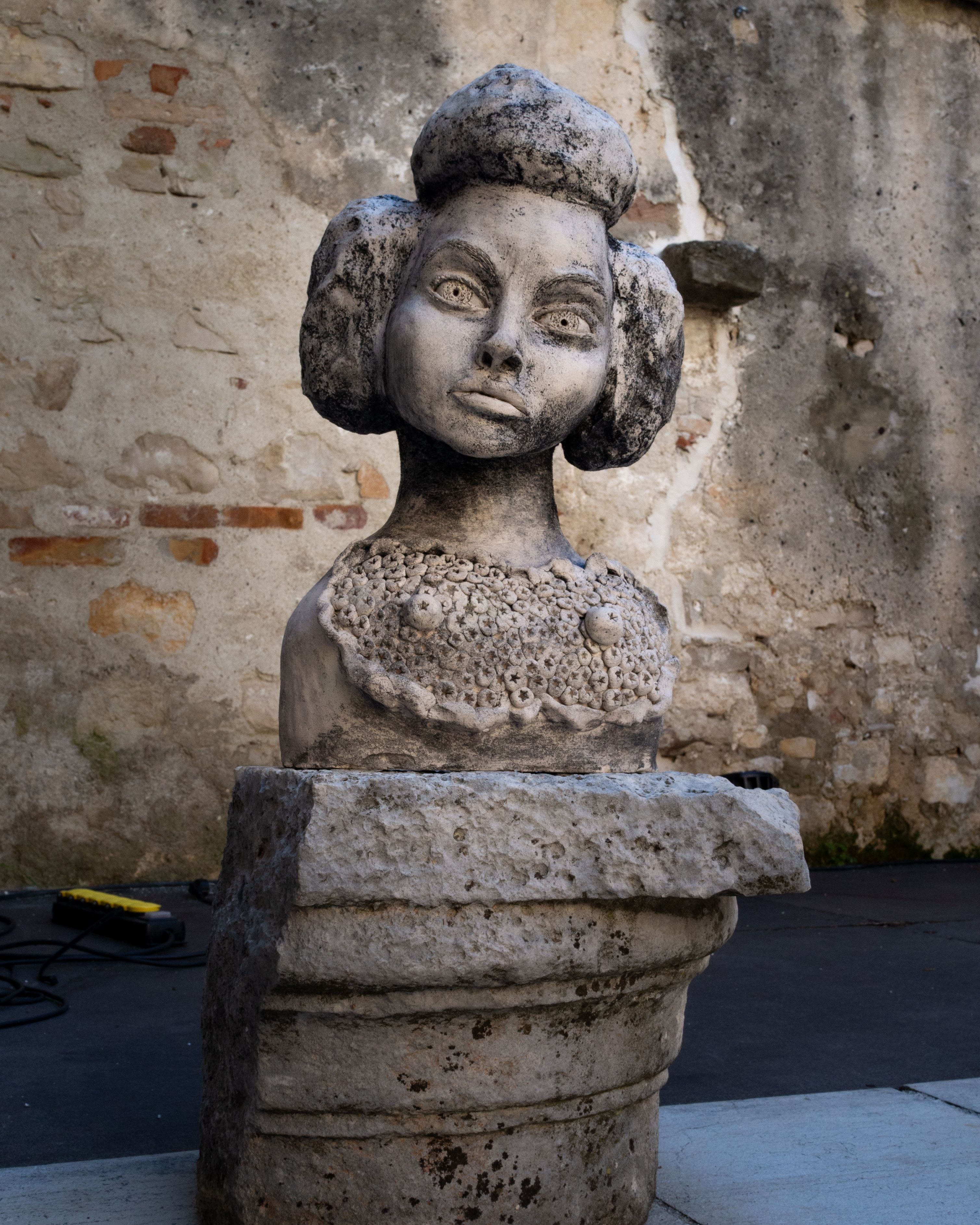 A stone bust sculpture set against an ancient wall in Poreč, revealing historical artistry.