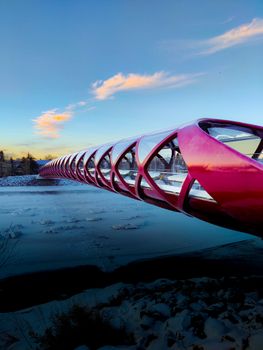 A stunning view of Peace Bridge over a snowy Bow River at sunset in Calgary, Alberta, Canada.