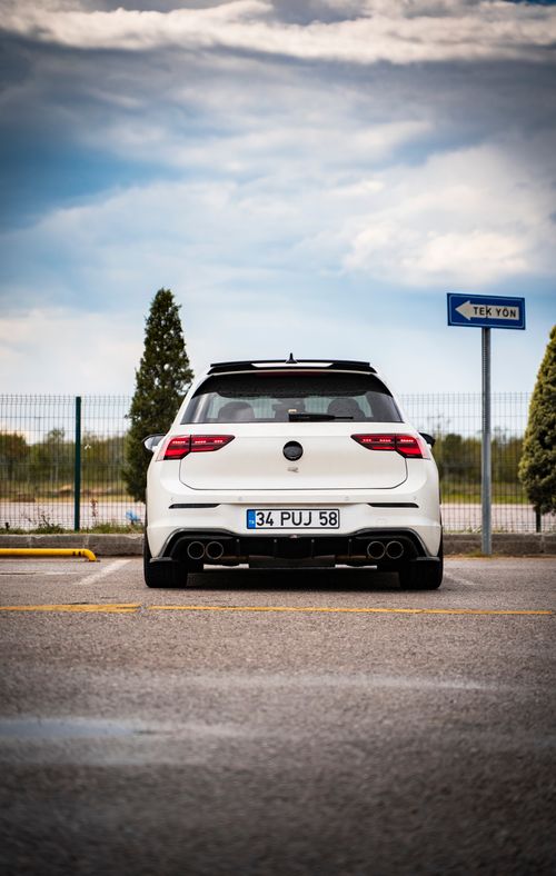 Free Rear view of a modern white car on a road with a clear blue sky backdrop, showcasing speed and design. Stock Photo