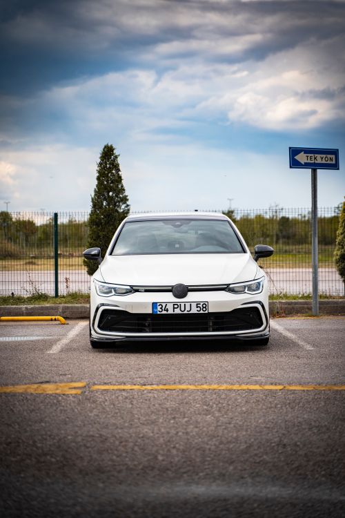 Free White car parked in an empty lot on a cloudy day, front view. Stock Photo