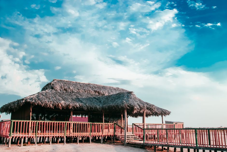 A serene beach hut with a thatched roof stands under a vibrant blue sky, embodying tranquility and nature.