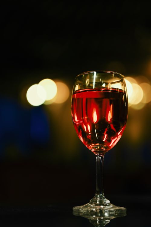 Free A glass of red wine elegantly set against a backdrop of soft bokeh lights, evoking a sophisticated evening ambiance. Stock Photo