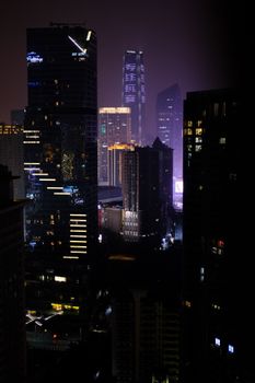 Dramatic view of a modern city's skyscrapers illuminated against the night sky, showcasing urban architecture.