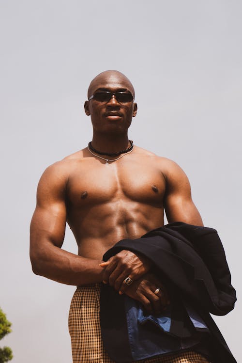 A shirtless man in sunglasses and a jacket