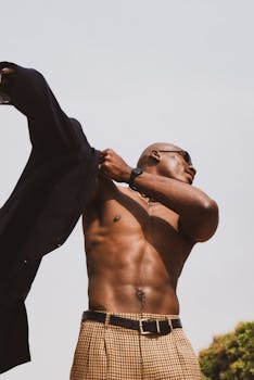 Athletic man with sunglasses posing outdoors, showcasing strength and style in Lagos.