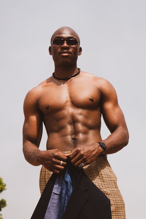 A shirtless man with sunglasses and a jacket