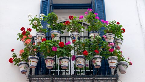 Vibrant geraniums adorn a balcony in Sitges, Spain, creating a bright and lively facade.