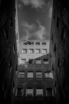 Black and white image of a building with a dramatic perspective and cloudy sky.