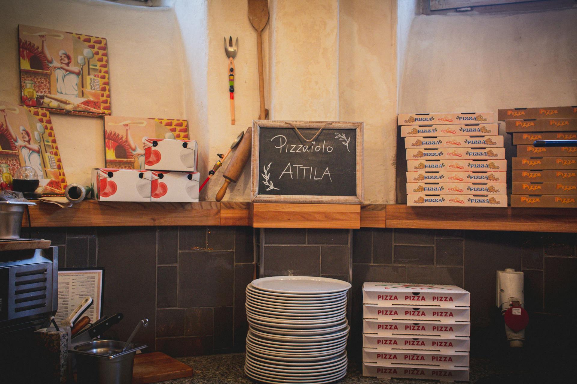 Cozy pizzeria interior with stacked pizza boxes and rustic decor on countertop.