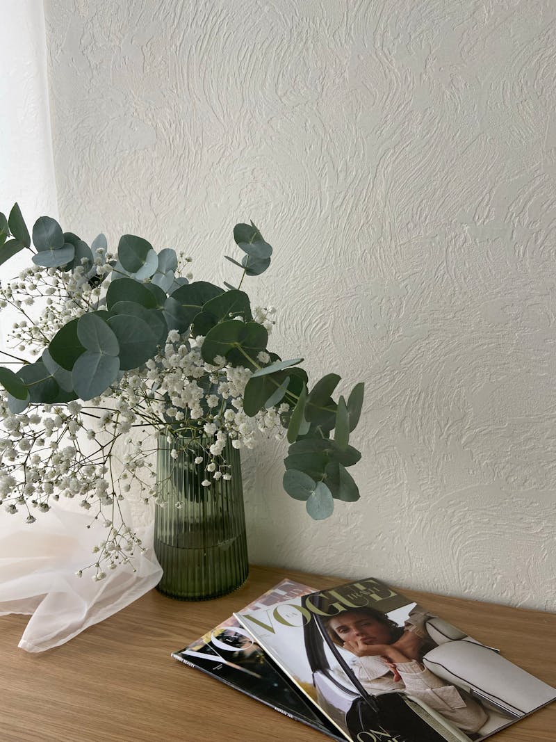 Eucalyptus and flowers in vase on wooden desk