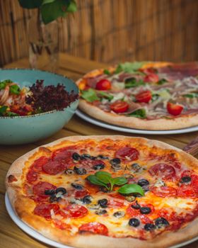 Delicious assorted pizzas with vibrant toppings served on a rustic wooden table, perfect for a hearty meal.