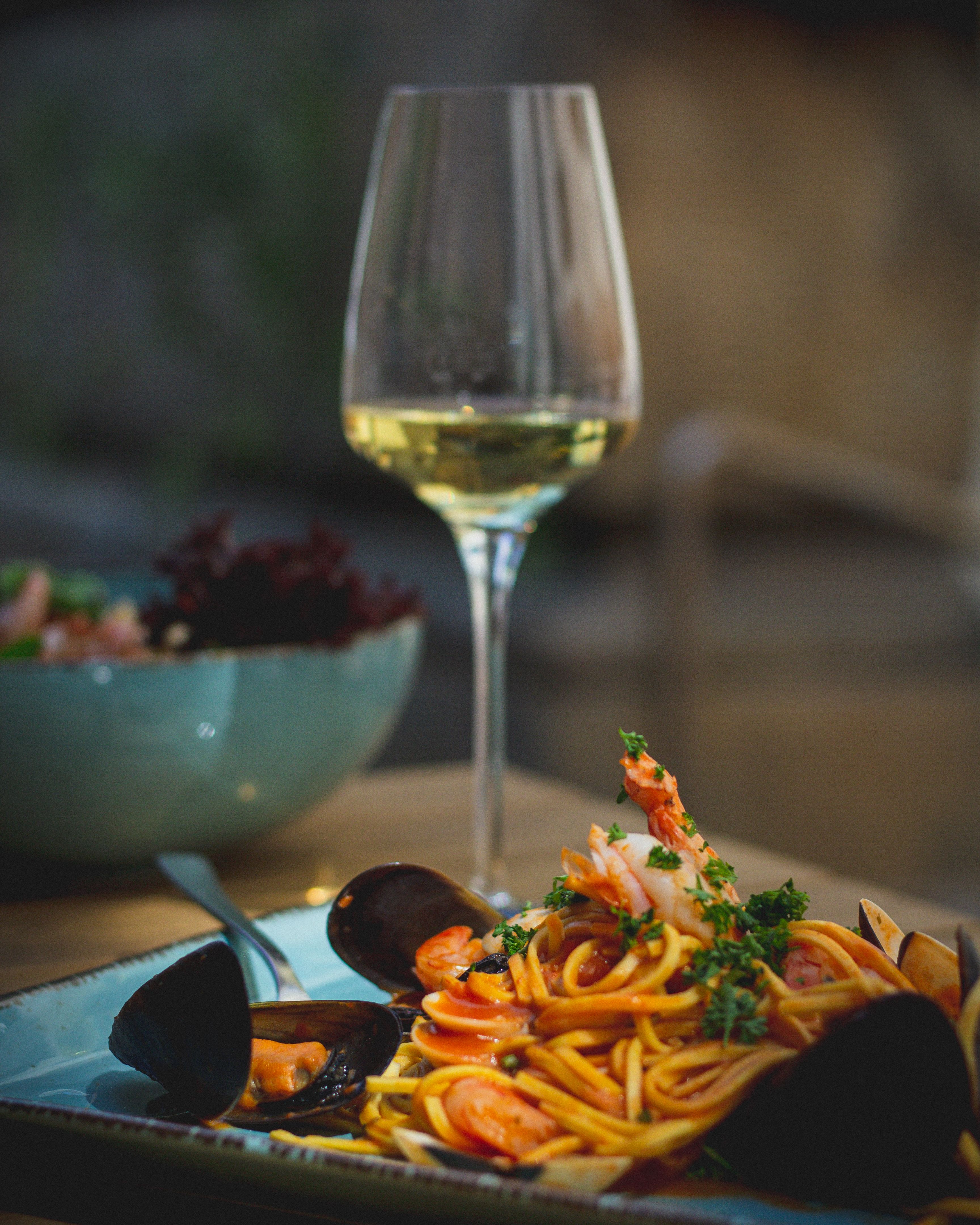 Delicious seafood pasta paired with a glass of white wine in a tasteful setting.