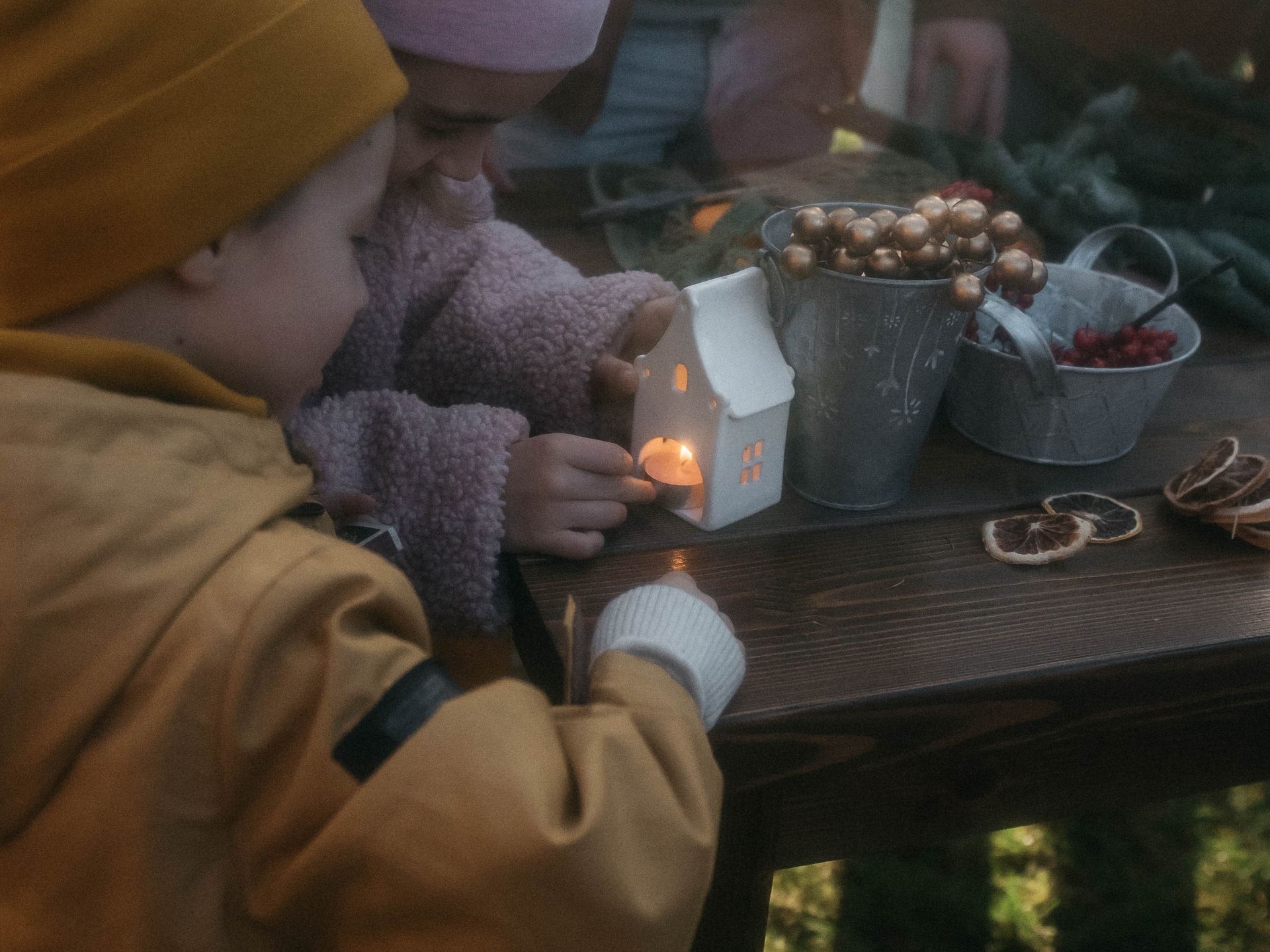 Children engaged in festive winter craft activities around a cozy table with decorations.