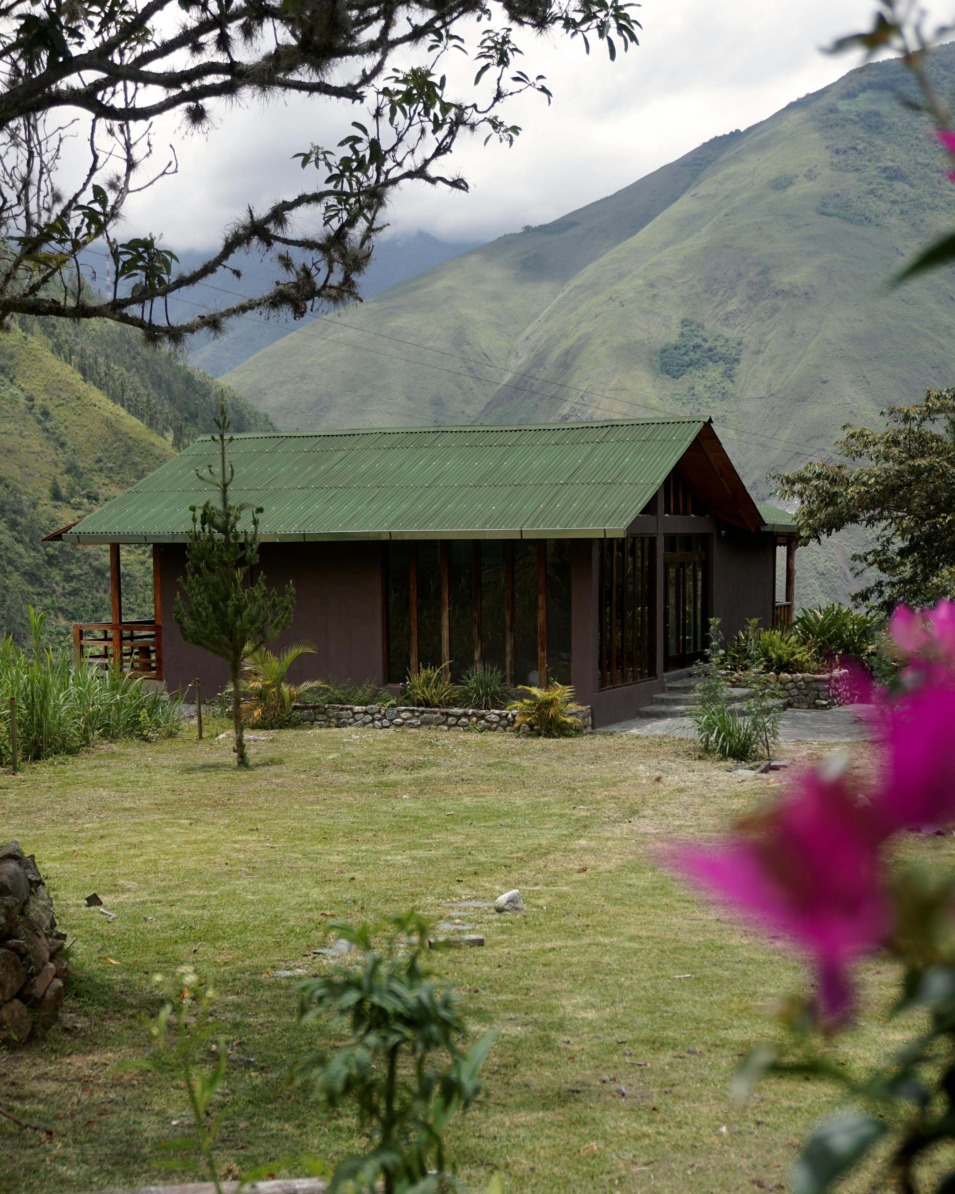Idyllic cabin in Cusco, Peru, surrounded by lush mountains and vibrant flowers.