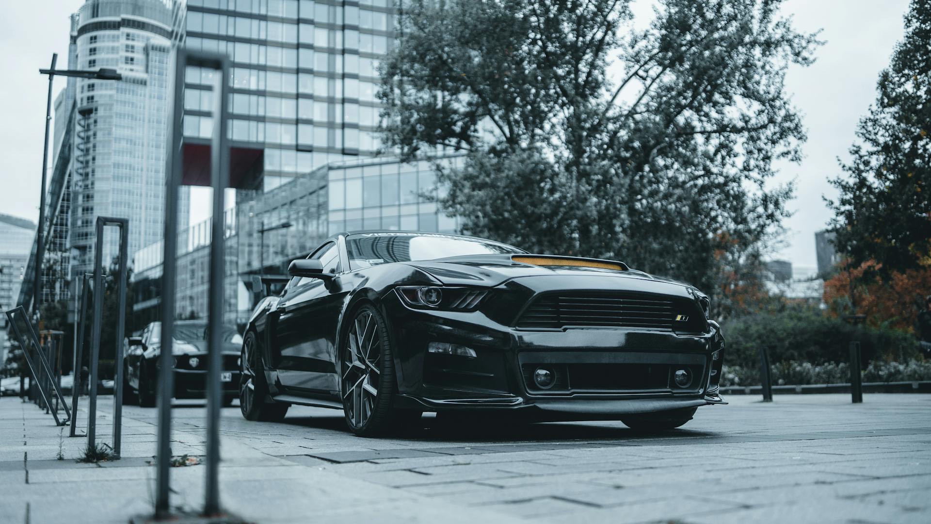 A shiny black sports car parked in the modern cityscape of Warsaw.