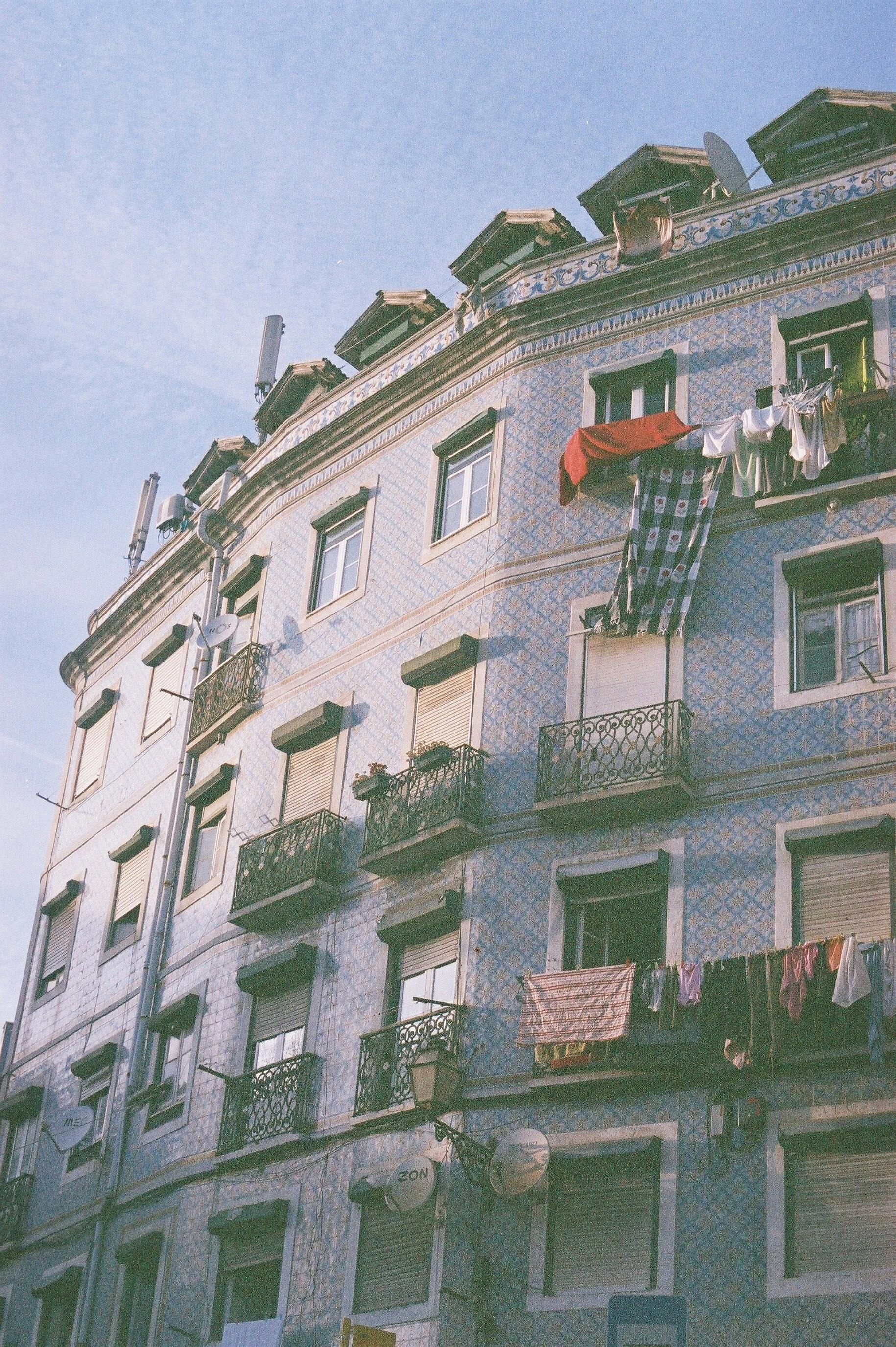 A captivating Lisbon building showcasing traditional architecture and hanging laundry under a clear sky.