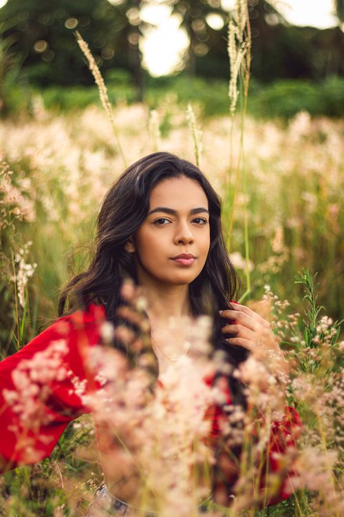 Free A young woman sits gracefully in a meadow, showcasing natural beauty and tranquility. Stock Photo