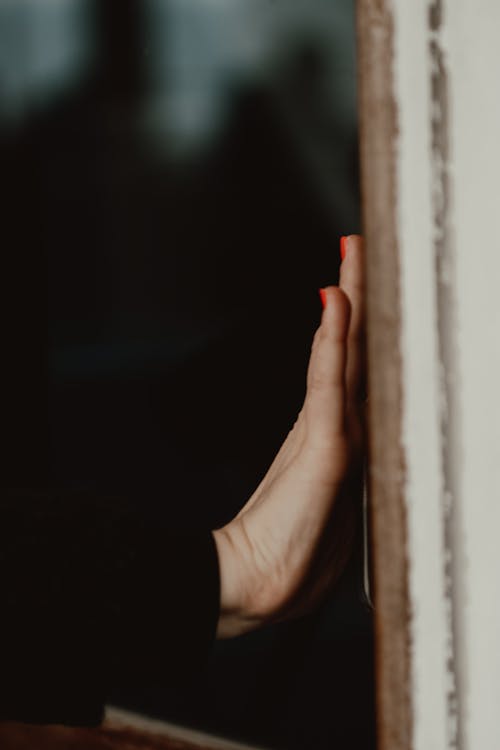Hand of a Woman Touching a Window Frame