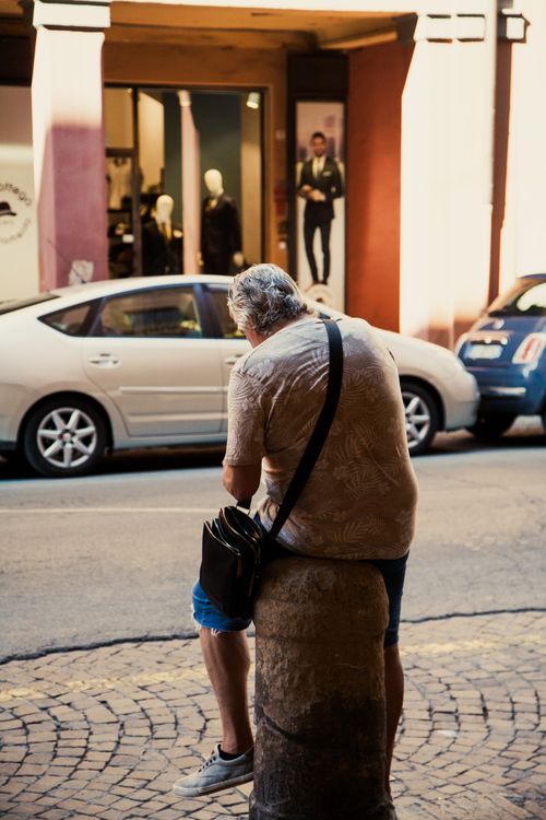Free Street scene of a man resting by parked cars in Bologna, Italy. Stock Photo