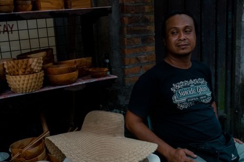 Free Man sitting next to handmade wooden bowls and wearing a woven hat in a rustic setting. Stock Photo