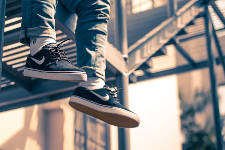 Crop Person Hanging Feet Over Stairs On Street