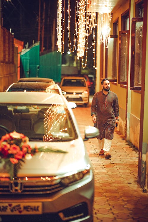 A man walking down a street with a car parked next to him