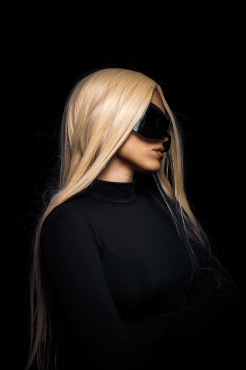 Free Striking portrait of woman wearing black clothing and sunglasses on dark background. Stock Photo