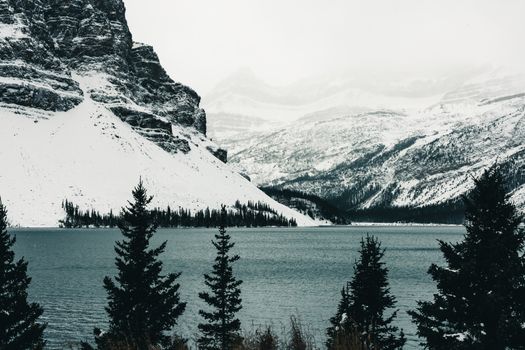 Majestic snowy mountains and serene lake in Jasper, AB, create a breathtaking winter landscape.