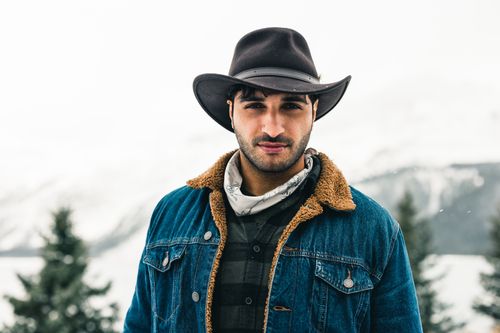 Free Man in denim jacket and cowboy hat stands outdoors in snowy Jasper, Canada. Stock Photo