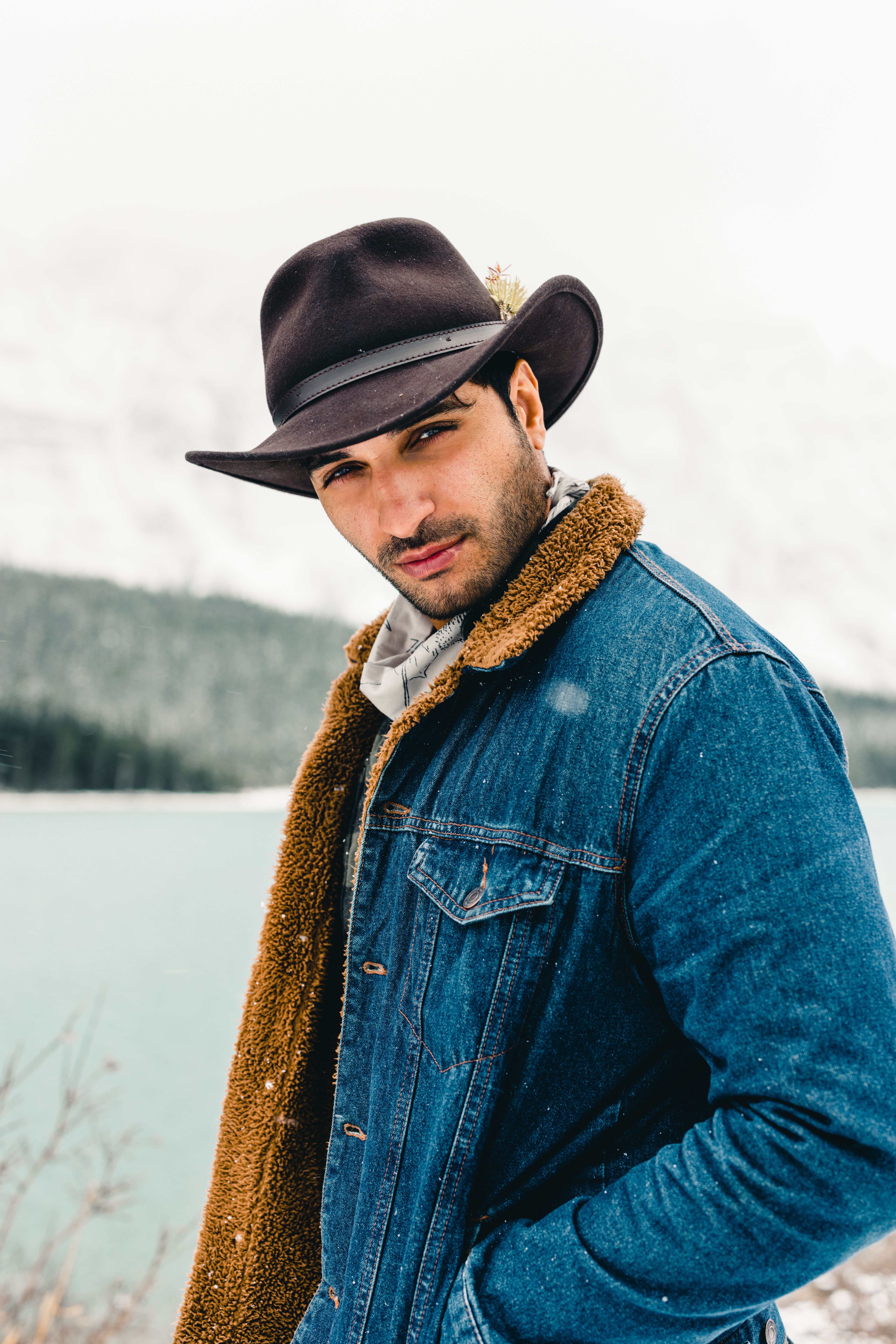 Portrait of a man in a denim jacket with a snowy mountain and lake background in Jasper, Canada.