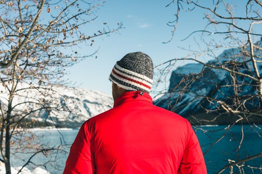 Man in red jacket and beanie enjoying winter landscape in Banff, Canada.