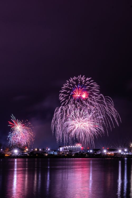 Free Colorful fireworks illuminate the night sky over Toronto's waterfront, reflecting in the calm river. Stock Photo