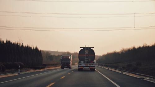 Free Long haul trucks traveling on a highway during sunset with a serene backdrop. Stock Photo