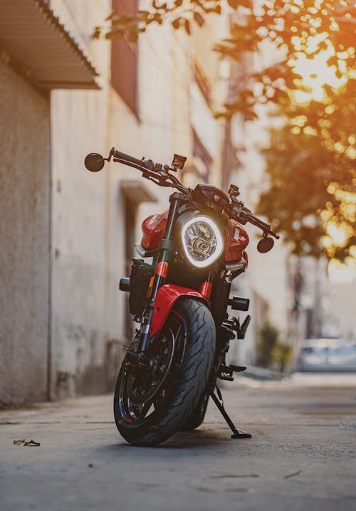 Red Ducati Monster Motorbike Parked Near a Building