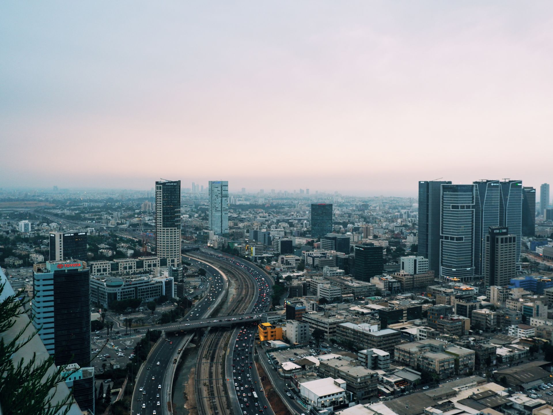 A breathtaking aerial view of Tel Aviv cityscape showcasing modern skyscrapers and a bustling highway at dusk.