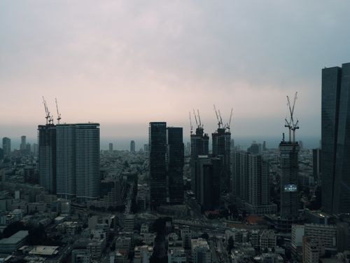 Free Aerial view of a city skyline with skyscrapers and construction cranes at dusk, showcasing urban development. Stock Photo