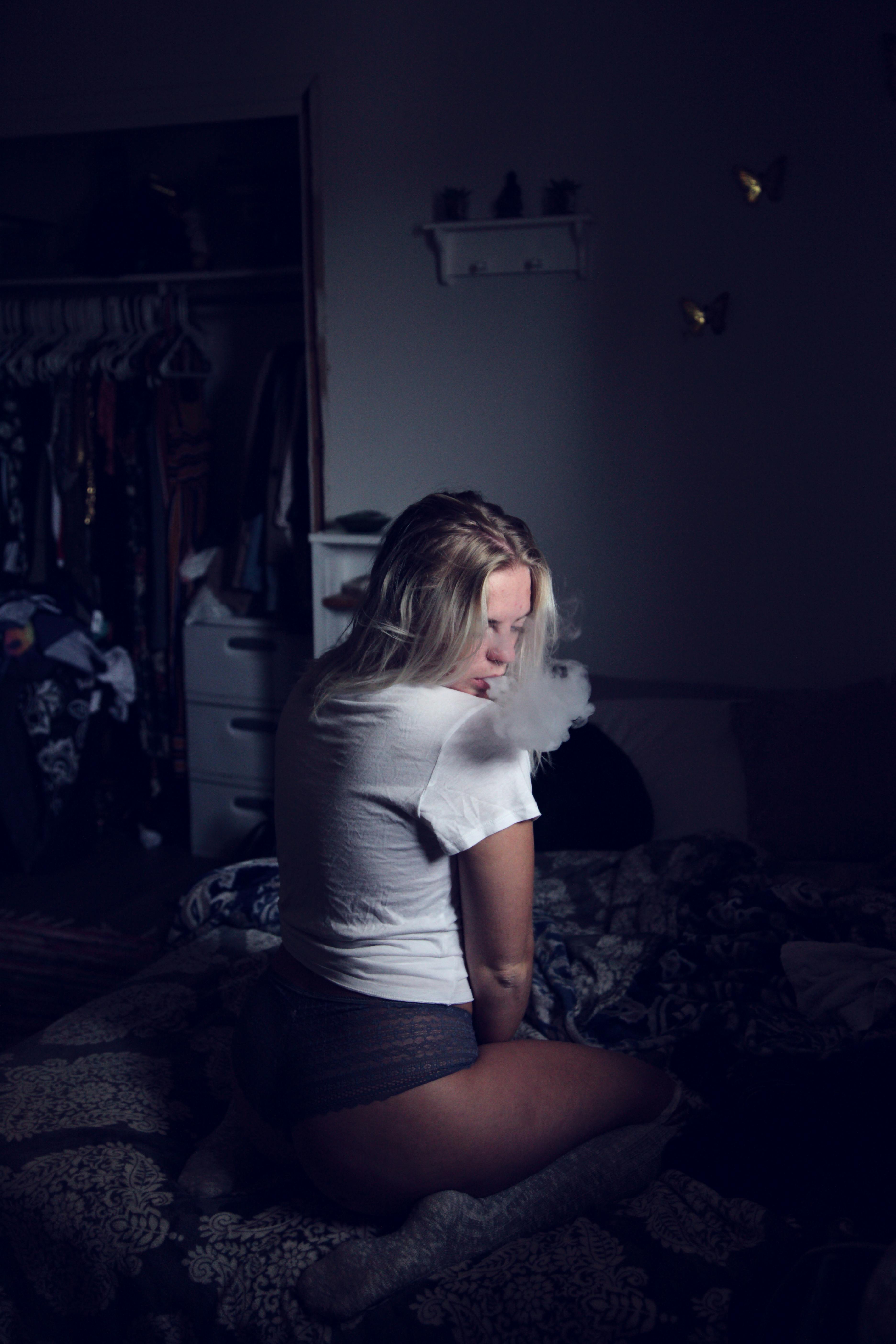 Woman Wearing White Shirt Sitting on Sofa and Smoking
