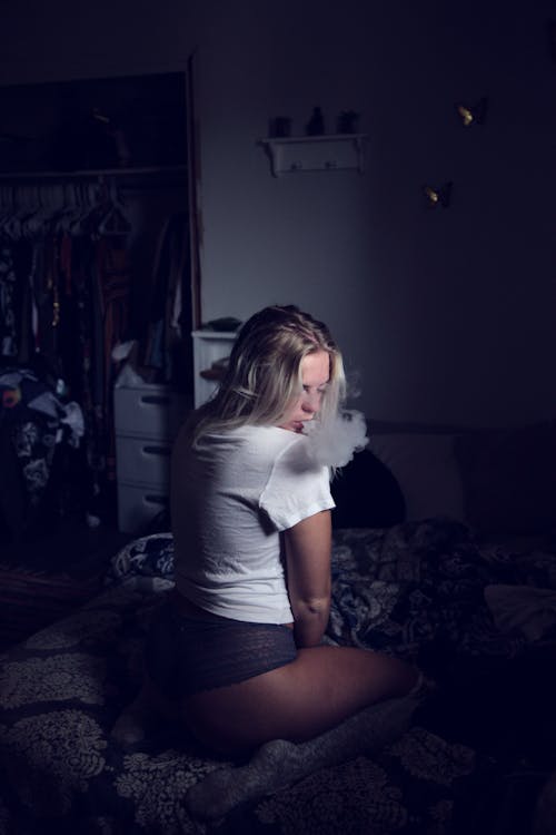 Free Woman Wearing White Shirt Sitting on Sofa and Smoking Stock Photo