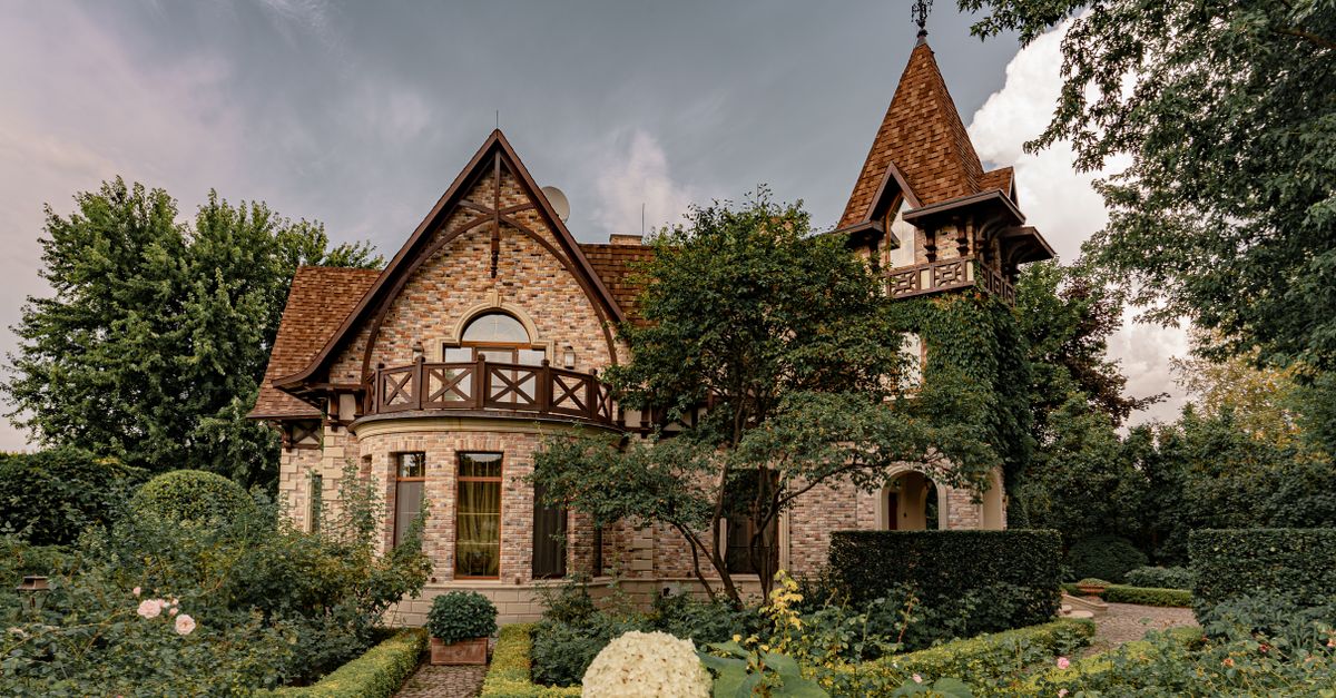 A picturesque traditional mansion surrounded by lush gardens and greenery, showcasing architectural beauty.