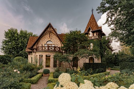 A picturesque traditional mansion surrounded by lush gardens and greenery, showcasing architectural beauty.