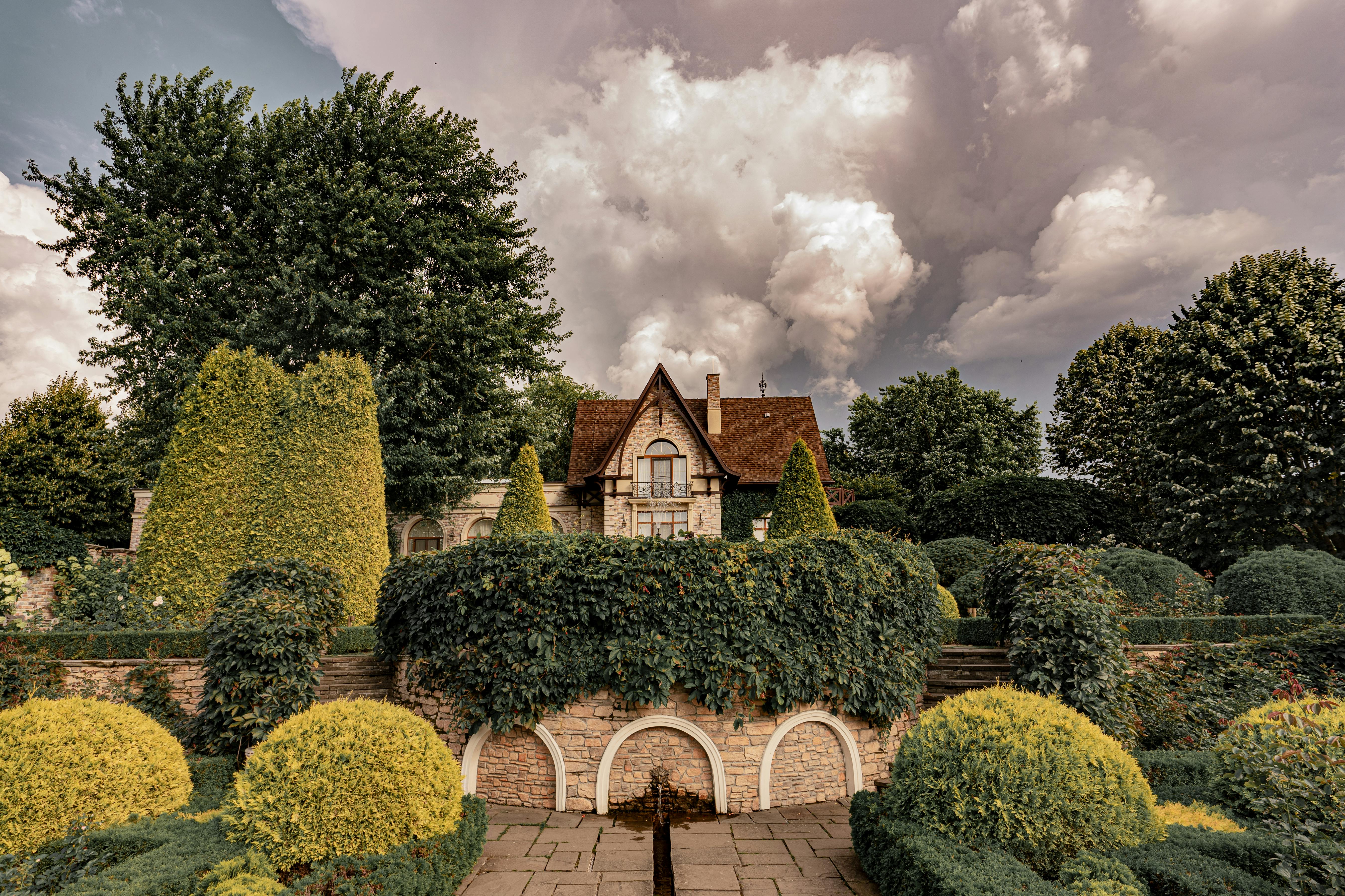 Jardín de mansión inglesa del período Tudor con setos recortados al atardecer