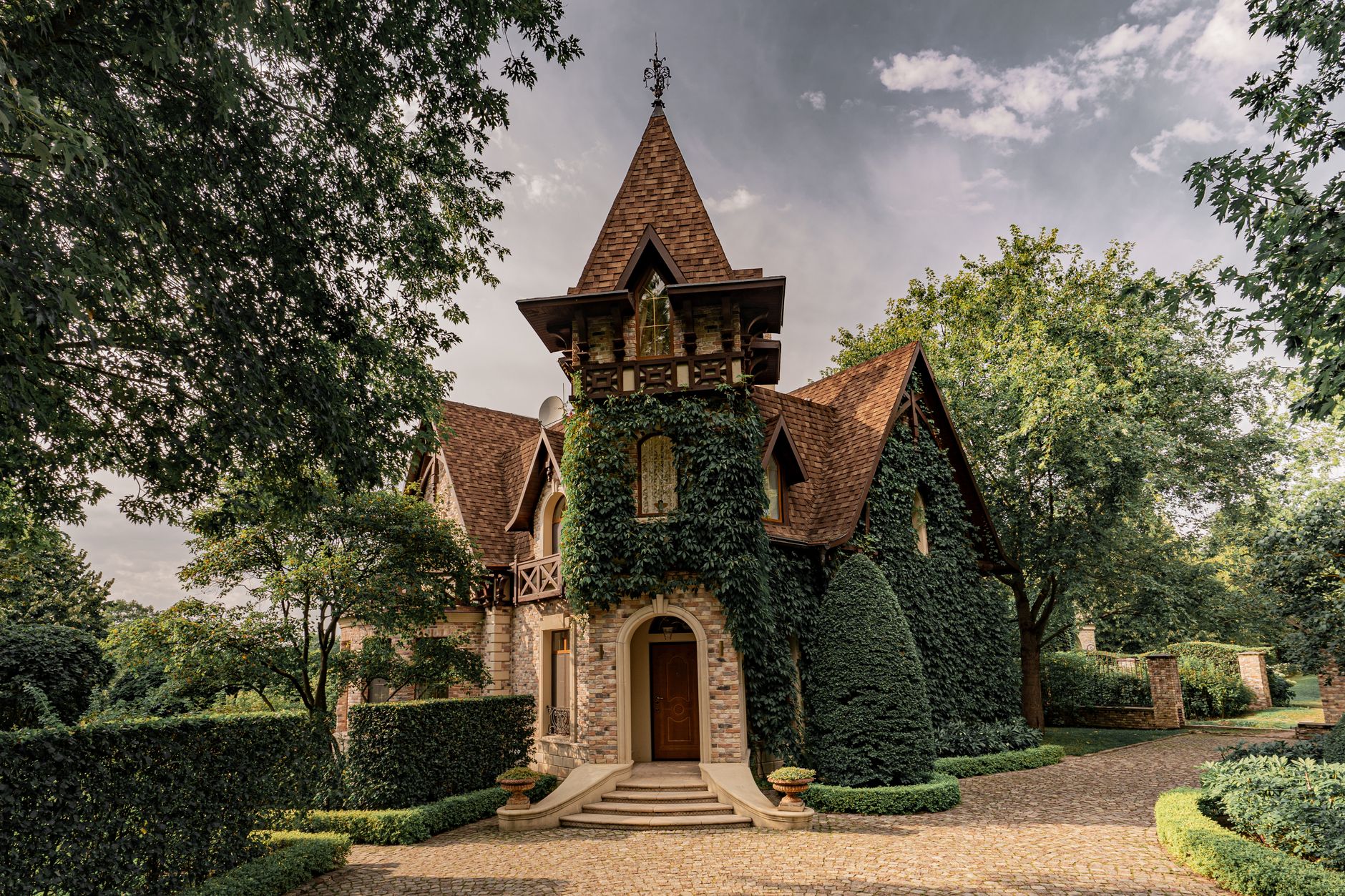 A picturesque ivy-covered manor house surrounded by lush gardens in a tranquil setting.