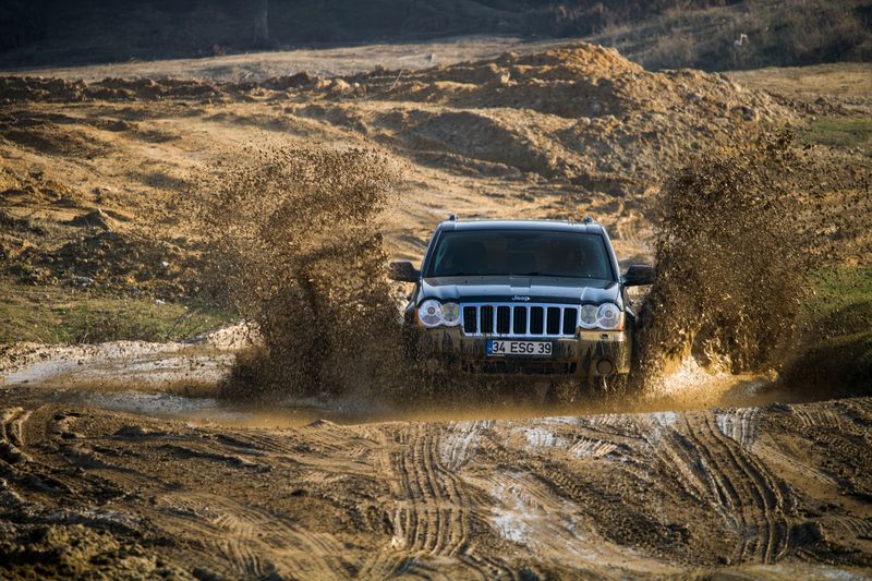 A jeep navigates through a muddy puddle, showcasing off-road adventure in İstanbul, Türkiye.