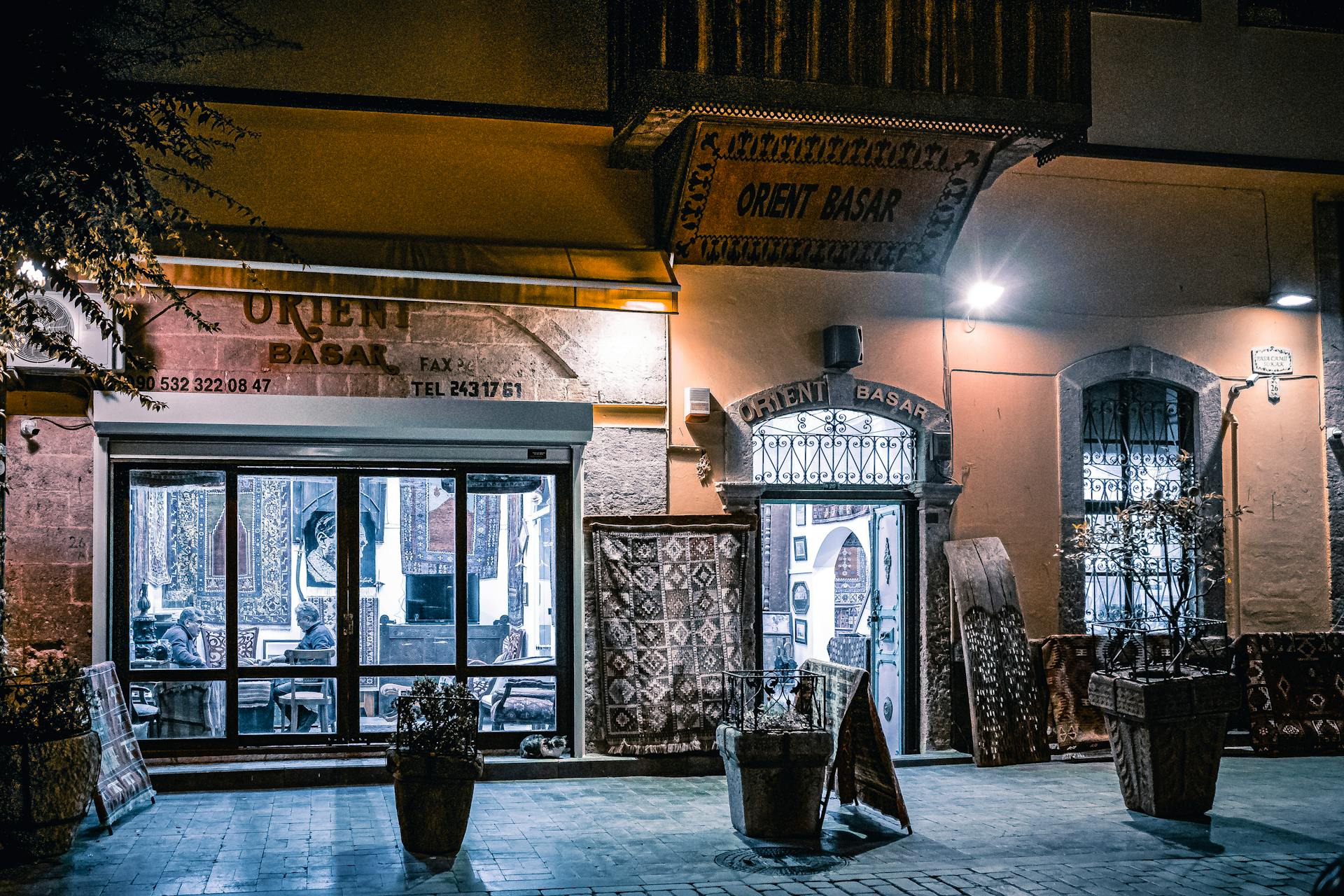 Elegant Orient Basar store exterior at night, showcasing traditional carpets and decor under soft lights.