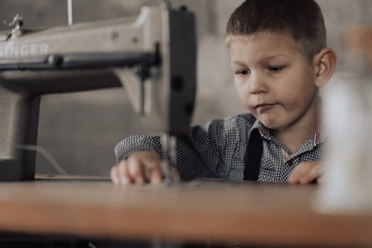 Boy Sitting and Sewing on Sewing Machine