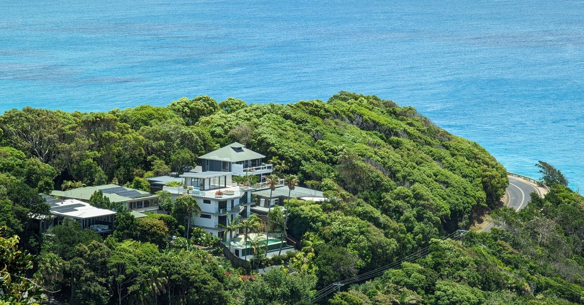 Stunning aerial view of houses nestled in lush greenery by the Byron Bay coastline.