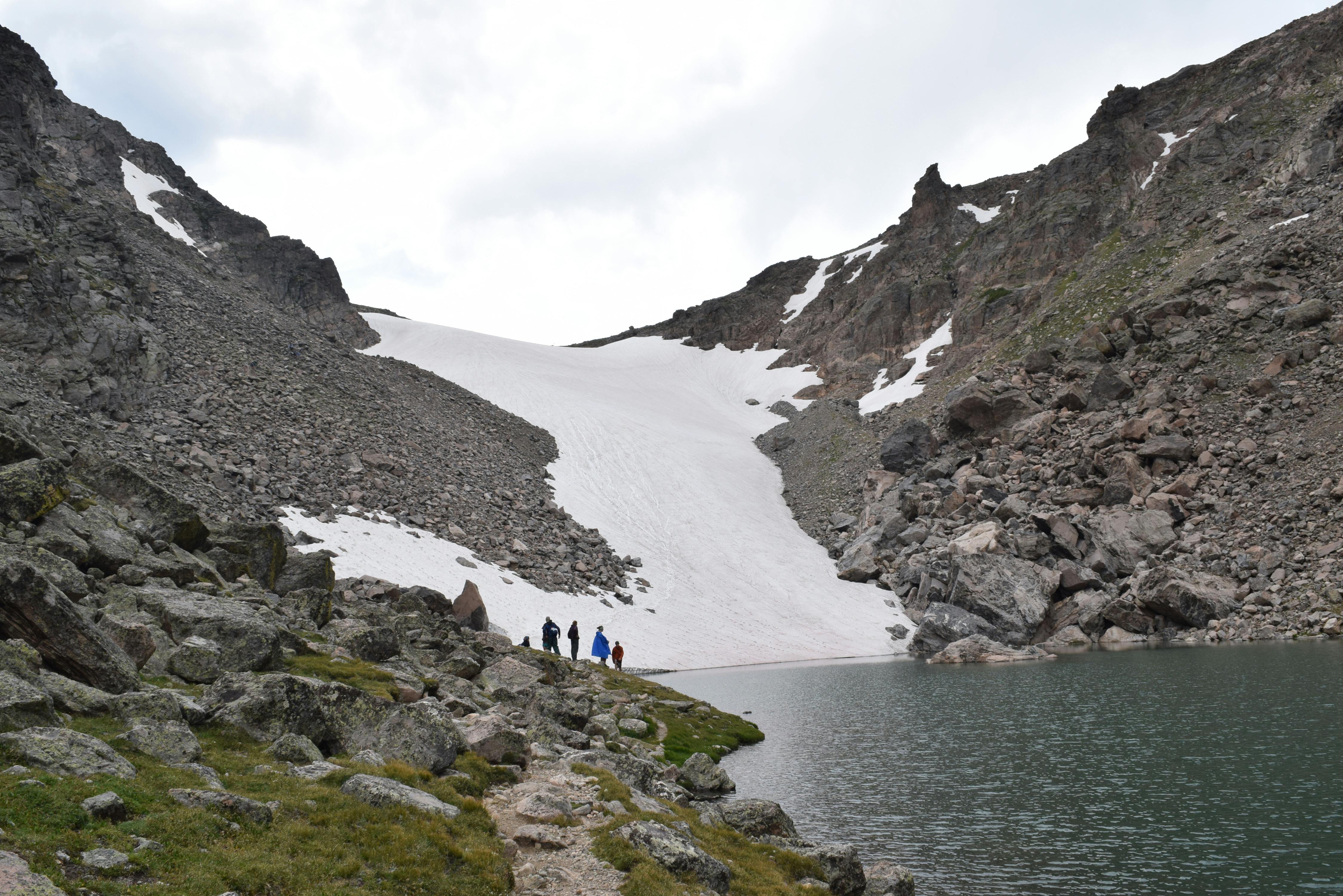 雪山景观附近，一个宁静的湖边有徒步旅行者